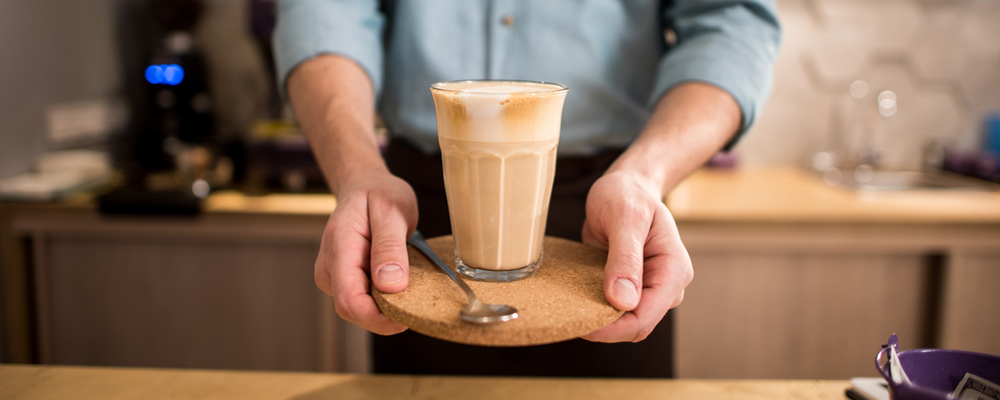 Cropped shot of barista with glass of ice coffee