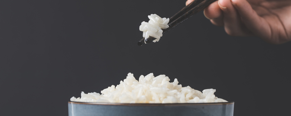 Cropped shot of woman taking freshly cooked rice from bowl