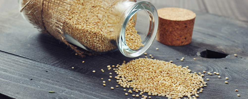 Raw quinoa seeds in the glass bottle on wooden background closeup