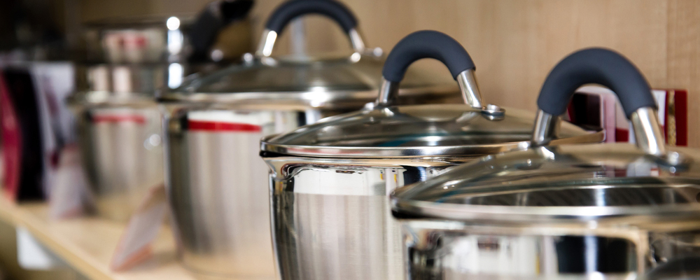 Stainless steel kitchenware set on shelves, shallow depth of field image