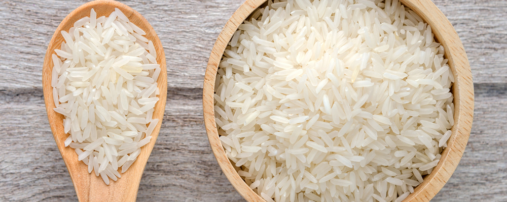 uncooked rice in bowl on white wood background