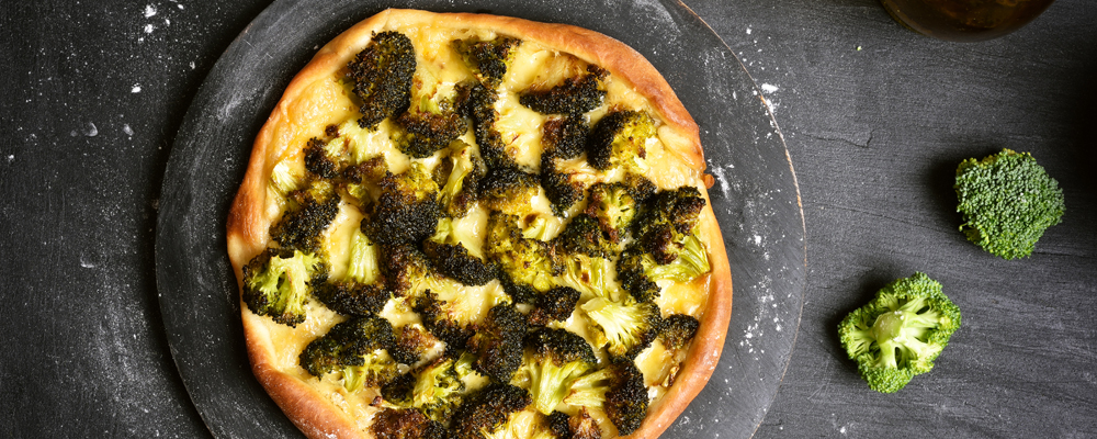 Pizza with broccoli on dark background, top view